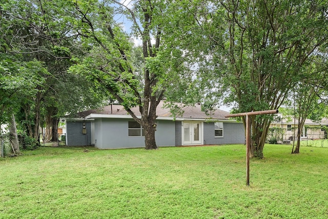 rear view of property featuring a lawn and french doors