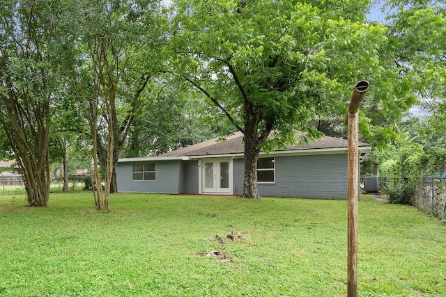 rear view of house featuring cooling unit, a yard, and french doors