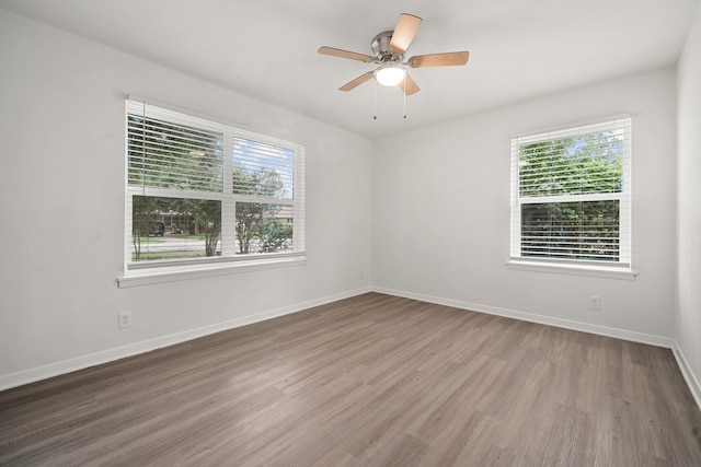 spare room featuring ceiling fan, a healthy amount of sunlight, and hardwood / wood-style flooring