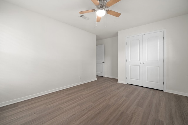 unfurnished bedroom featuring a closet, ceiling fan, and dark hardwood / wood-style flooring