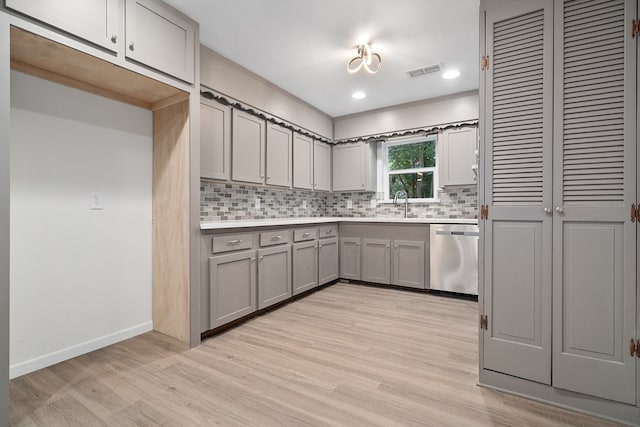 kitchen featuring tasteful backsplash, gray cabinets, stainless steel dishwasher, and light wood-type flooring