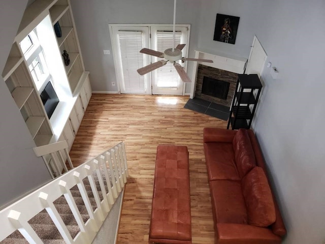 living room featuring ceiling fan, light hardwood / wood-style flooring, and a fireplace