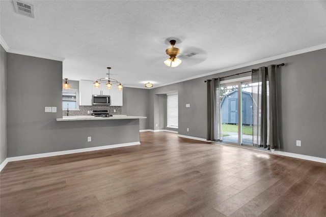 unfurnished living room featuring ceiling fan, wood-type flooring, ornamental molding, and a textured ceiling