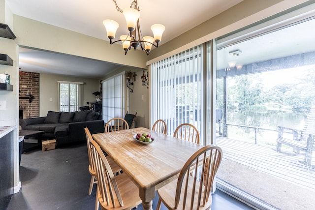 dining room featuring a brick fireplace and a notable chandelier