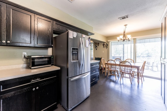 kitchen with hanging light fixtures, appliances with stainless steel finishes, light countertops, and a notable chandelier