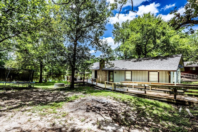 rear view of property featuring a trampoline and a deck