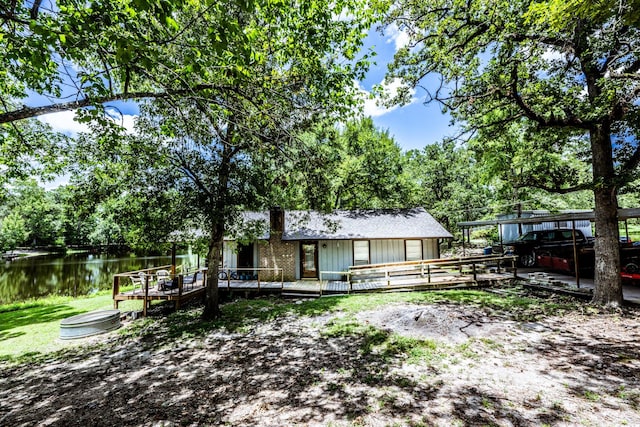 rear view of property featuring a deck with water view and a detached carport