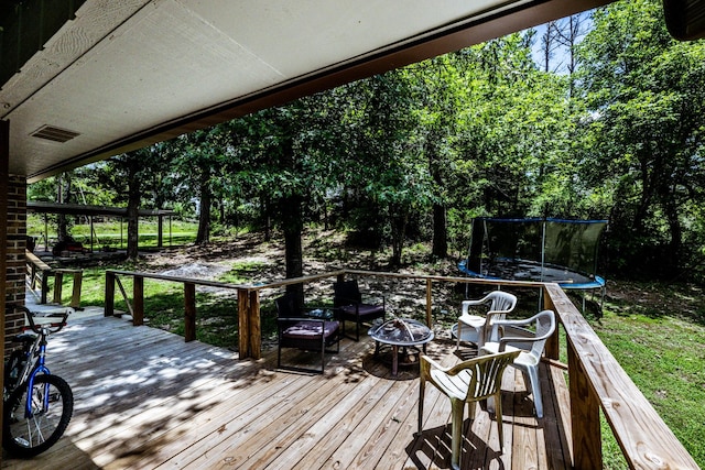 wooden deck with a trampoline and a fire pit