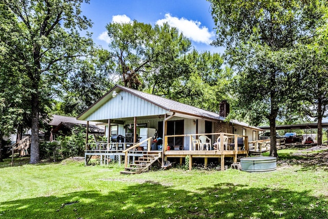 rear view of house with a chimney, a deck, and a yard