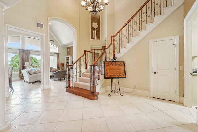 tiled entrance foyer featuring a notable chandelier and high vaulted ceiling