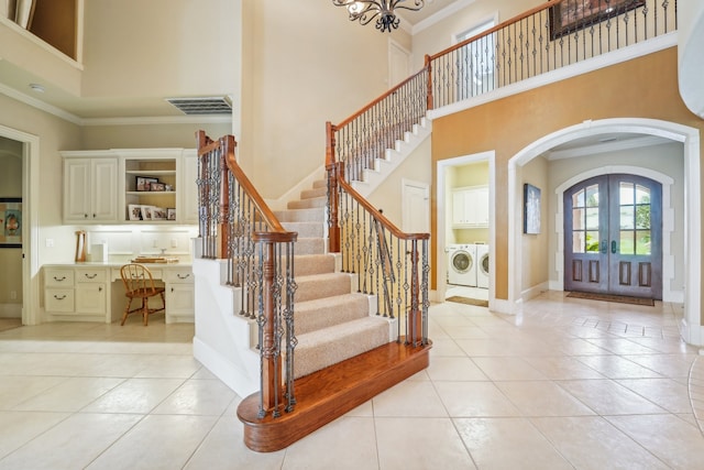 foyer featuring separate washer and dryer, crown molding, french doors, light tile patterned floors, and a high ceiling