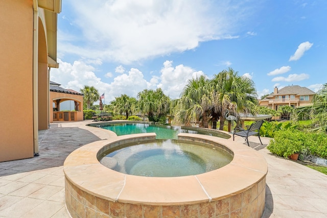 view of swimming pool featuring an in ground hot tub and a patio area