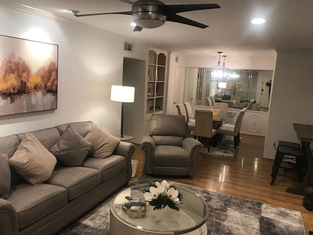 living room featuring ceiling fan with notable chandelier, dark hardwood / wood-style flooring, and ornamental molding