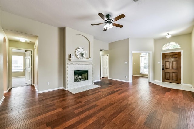 unfurnished living room with ceiling fan, a fireplace, dark hardwood / wood-style floors, and a healthy amount of sunlight