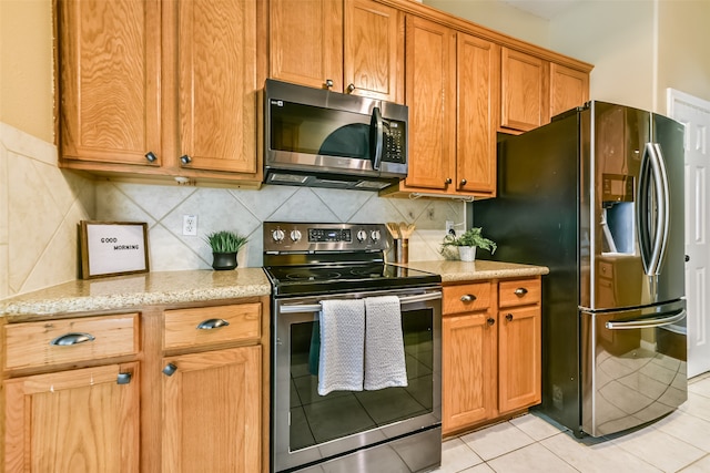 kitchen with backsplash, appliances with stainless steel finishes, light tile patterned floors, and light stone countertops