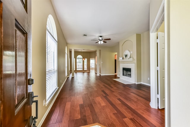 unfurnished living room featuring dark wood-type flooring, a fireplace, and ceiling fan