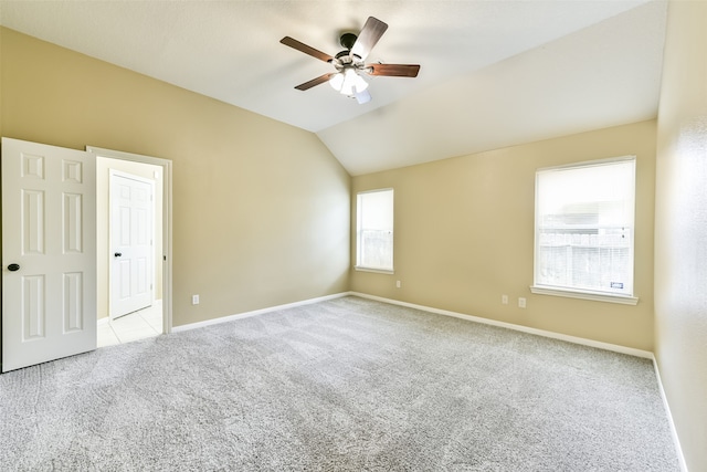 empty room with ceiling fan, vaulted ceiling, and light colored carpet