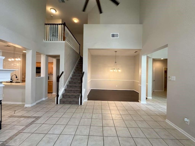 foyer with a towering ceiling, light tile patterned floors, sink, and a notable chandelier