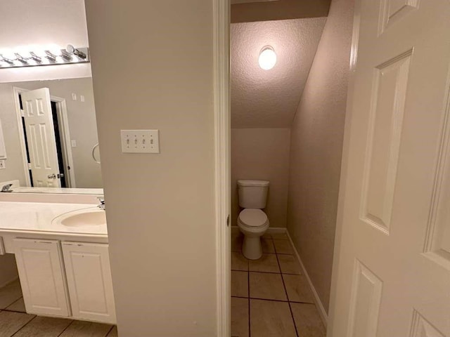 bathroom with tile patterned flooring, vanity, toilet, and a textured ceiling