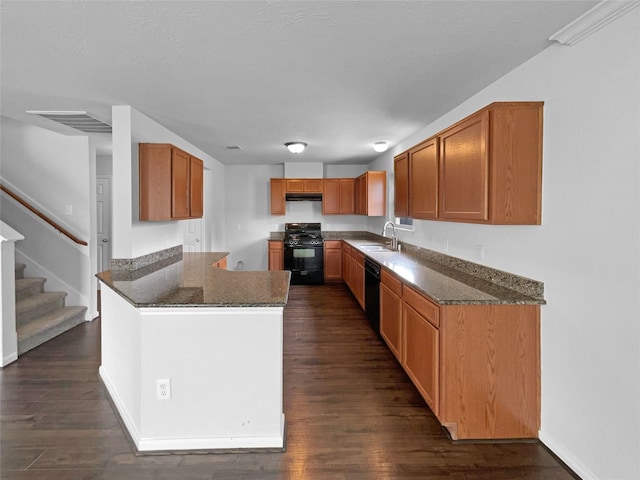 kitchen featuring black appliances, dark hardwood / wood-style flooring, sink, and dark stone countertops