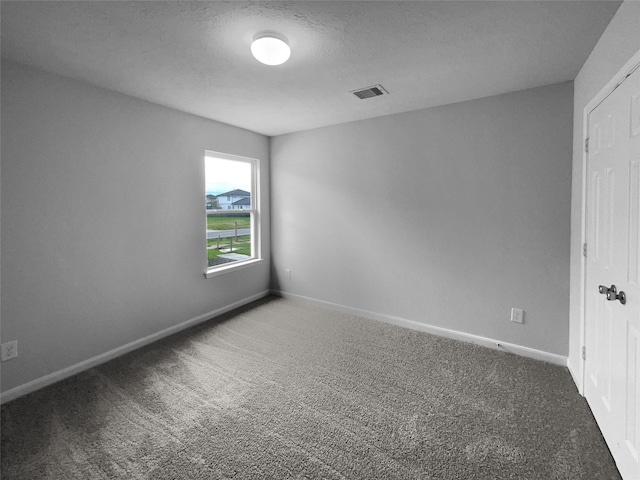 spare room with a textured ceiling and dark colored carpet