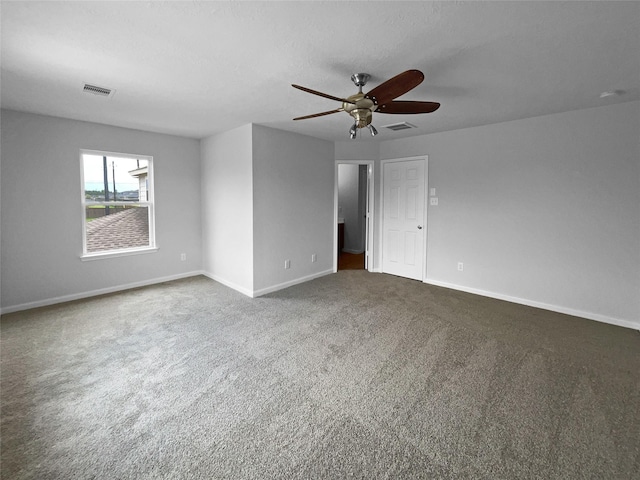 empty room with ceiling fan and dark carpet