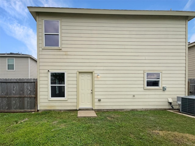 rear view of property featuring central air condition unit and a yard