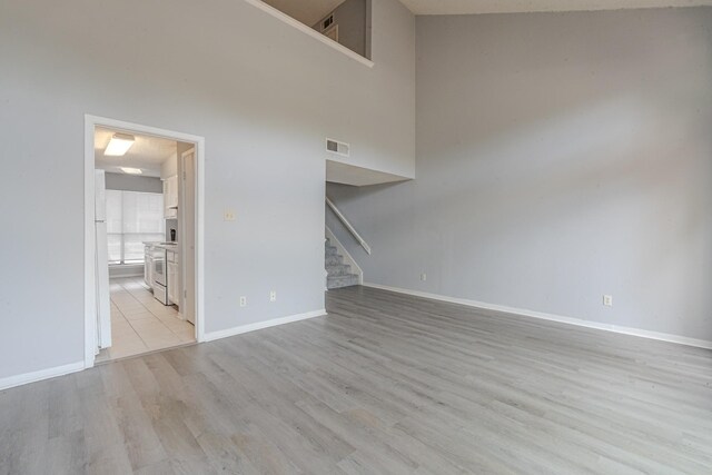 unfurnished living room featuring light hardwood / wood-style floors and a high ceiling