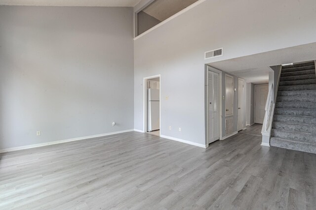 unfurnished living room featuring high vaulted ceiling and light wood-type flooring