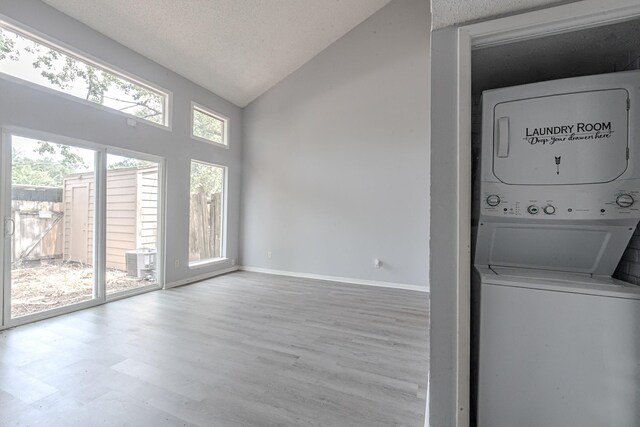 laundry room with wood-type flooring, a textured ceiling, and stacked washer and clothes dryer