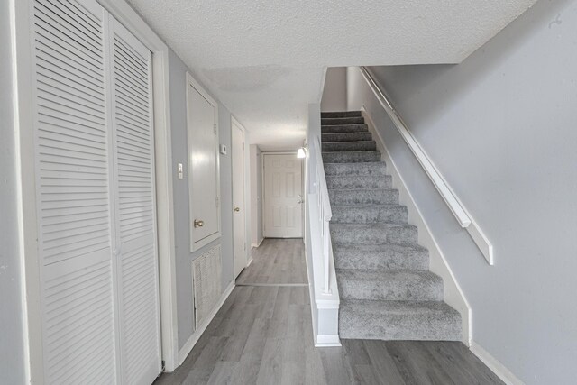 stairway featuring a textured ceiling and hardwood / wood-style flooring