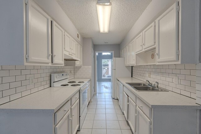 kitchen with light tile patterned floors, sink, white cabinets, and white appliances