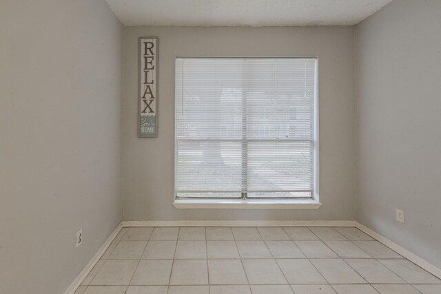 unfurnished room with a textured ceiling and light tile patterned floors