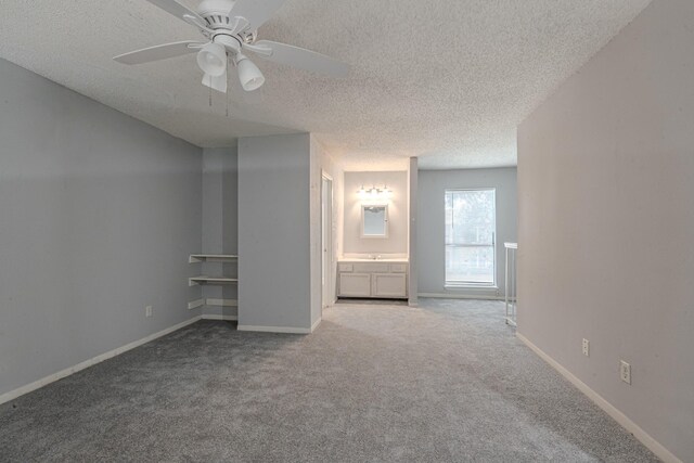 unfurnished bedroom with a textured ceiling, ceiling fan, ensuite bathroom, and carpet