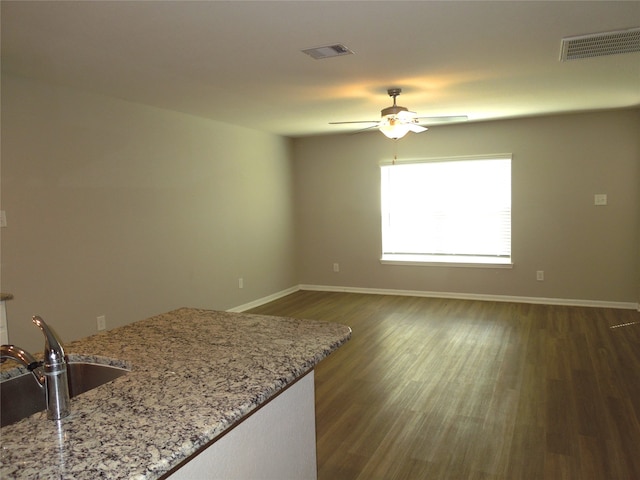 interior space with sink, dark hardwood / wood-style floors, ceiling fan, and light stone countertops