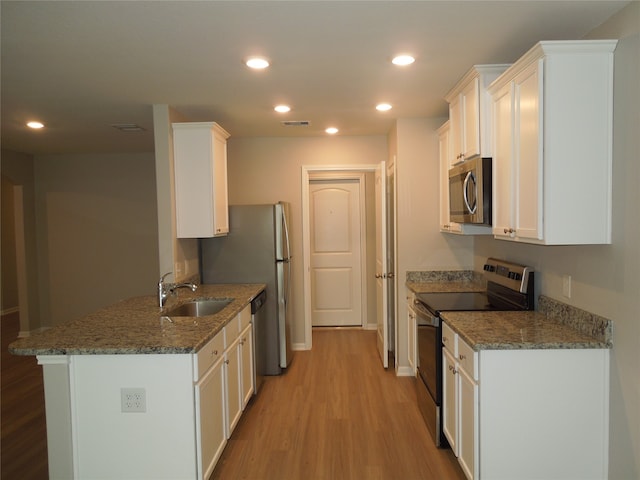 kitchen with white cabinetry, stainless steel appliances, light wood-type flooring, sink, and kitchen peninsula