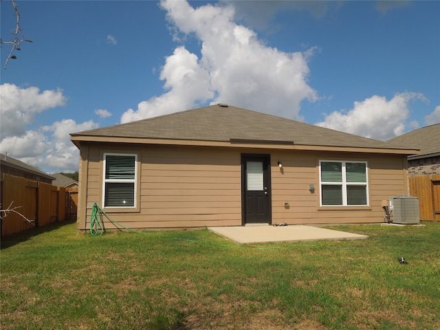 back of property with central AC, a patio, and a lawn