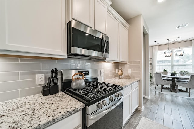 kitchen featuring light stone countertops, white cabinets, backsplash, and appliances with stainless steel finishes