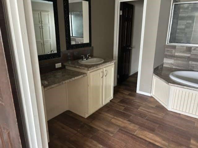 bathroom with vanity, a washtub, hardwood / wood-style flooring, and tasteful backsplash