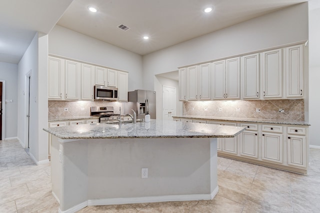 kitchen with appliances with stainless steel finishes, a kitchen island with sink, and white cabinets