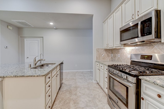 kitchen with light stone countertops, backsplash, stainless steel appliances, and sink