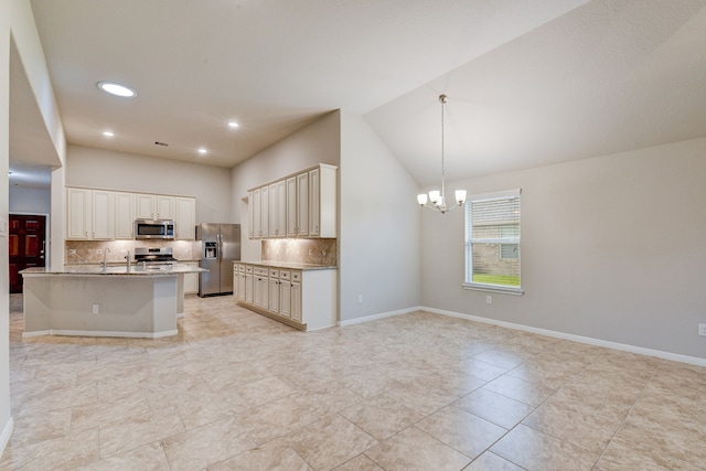 kitchen with lofted ceiling, an inviting chandelier, decorative light fixtures, stainless steel appliances, and a kitchen island with sink