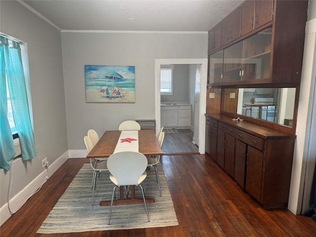 dining room featuring crown molding, dark hardwood / wood-style flooring, and sink