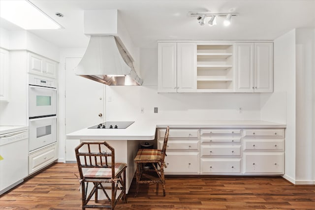 kitchen featuring white cabinetry, hardwood / wood-style floors, white appliances, a breakfast bar, and track lighting