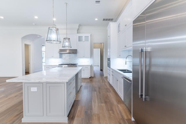 kitchen with appliances with stainless steel finishes, tasteful backsplash, a kitchen island, white cabinets, and sink