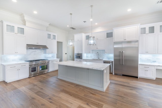 kitchen with pendant lighting, a kitchen island, white cabinetry, high end appliances, and sink