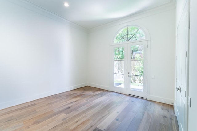 empty room with french doors, ornamental molding, and light hardwood / wood-style flooring