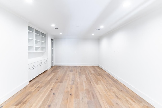 spare room featuring light hardwood / wood-style flooring and built in shelves