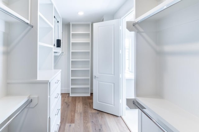 walk in closet with light hardwood / wood-style flooring