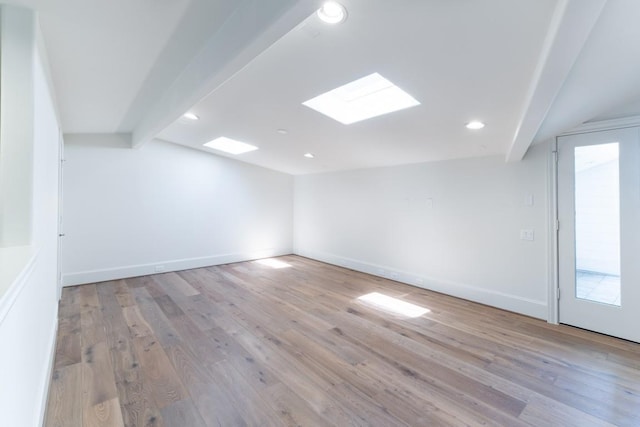 unfurnished room with light wood-type flooring and beamed ceiling